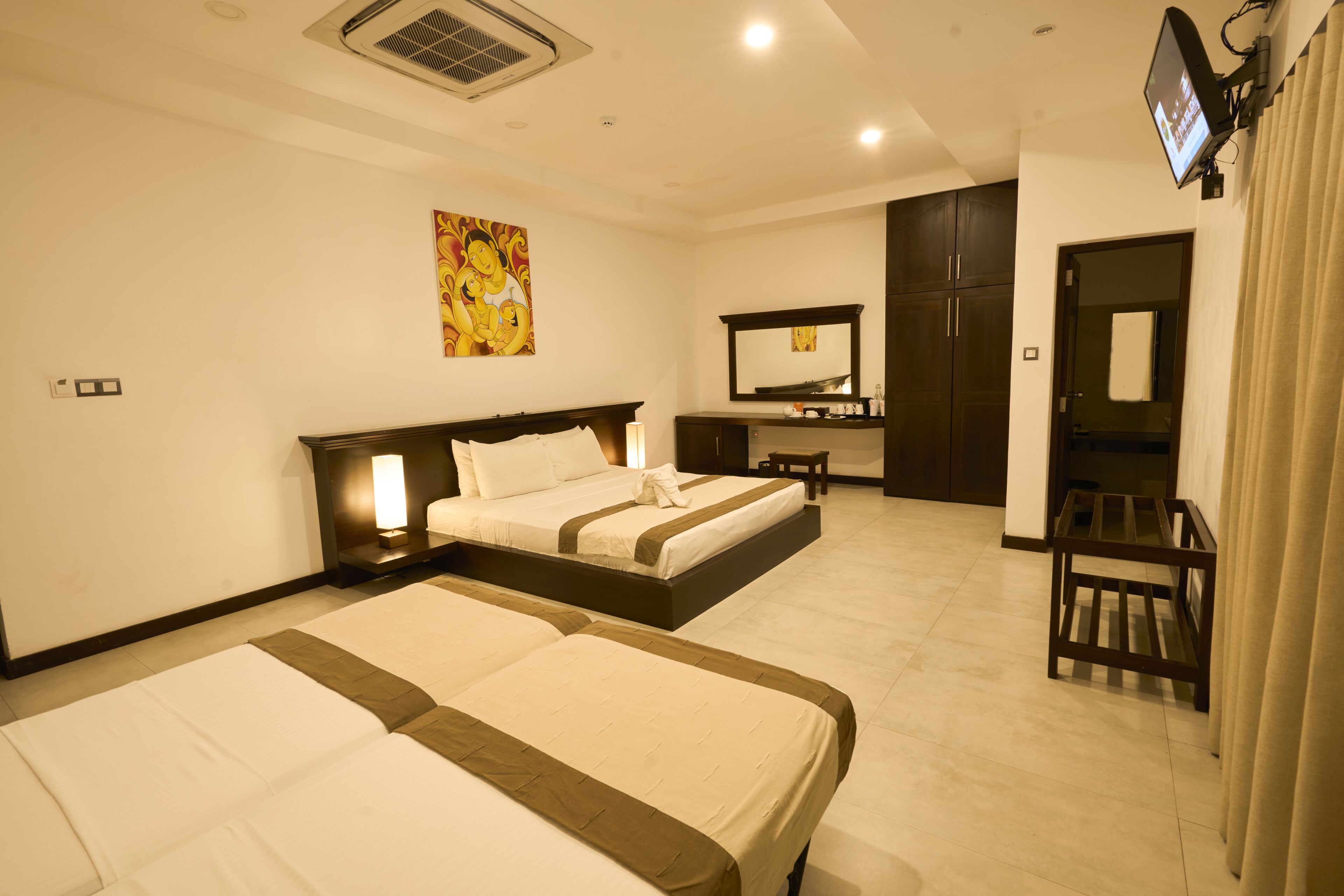 A hotel room with two beds, a desk, a chair, a television, and a bathroom door.