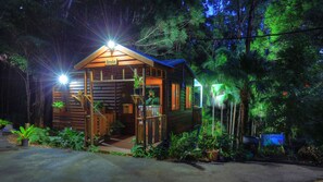 A wooden cabin with a reception area, surrounded by lush greenery and potted plants.