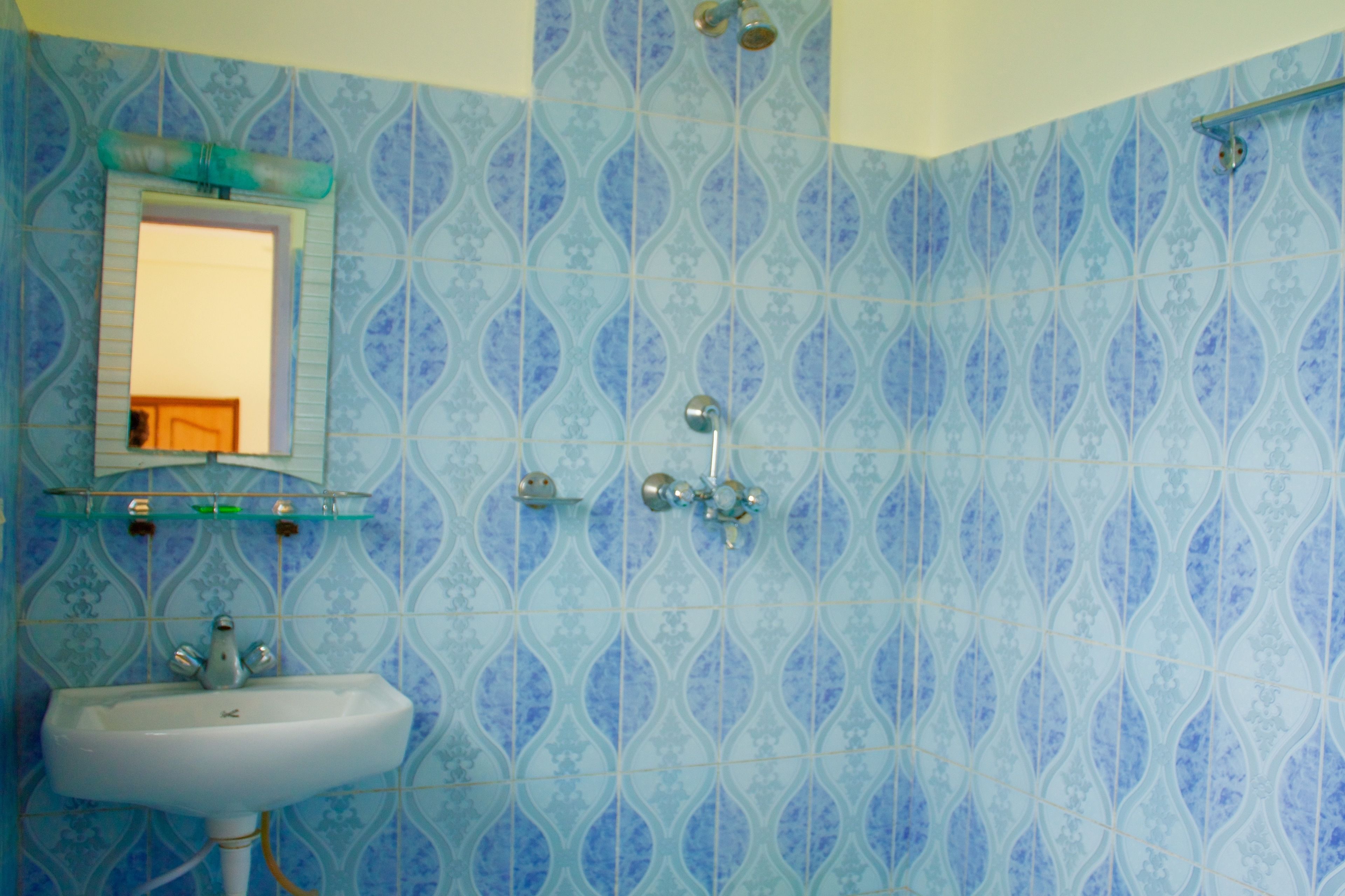 A bathroom with a sink, mirror, and shower.