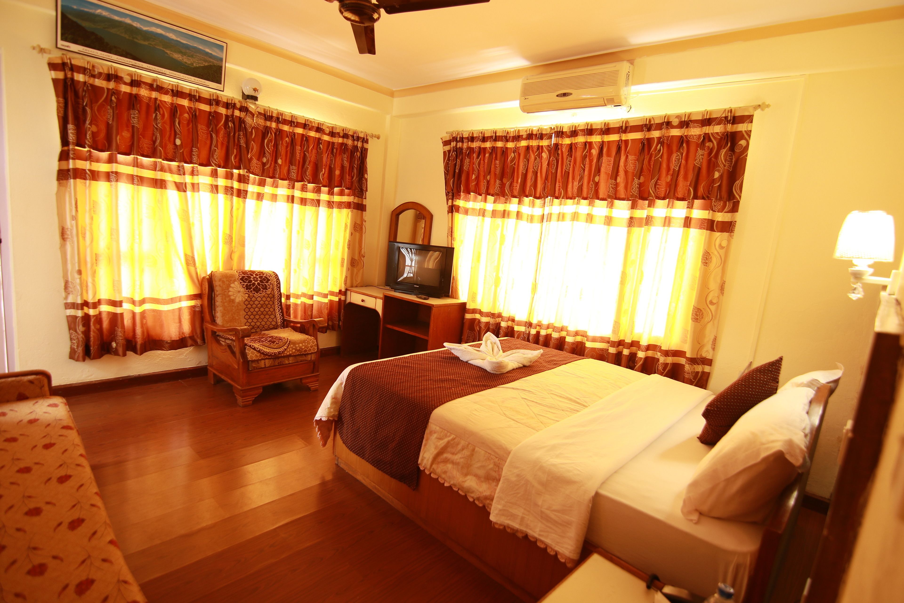 A hotel room with a bed, a desk, a chair, and curtains.