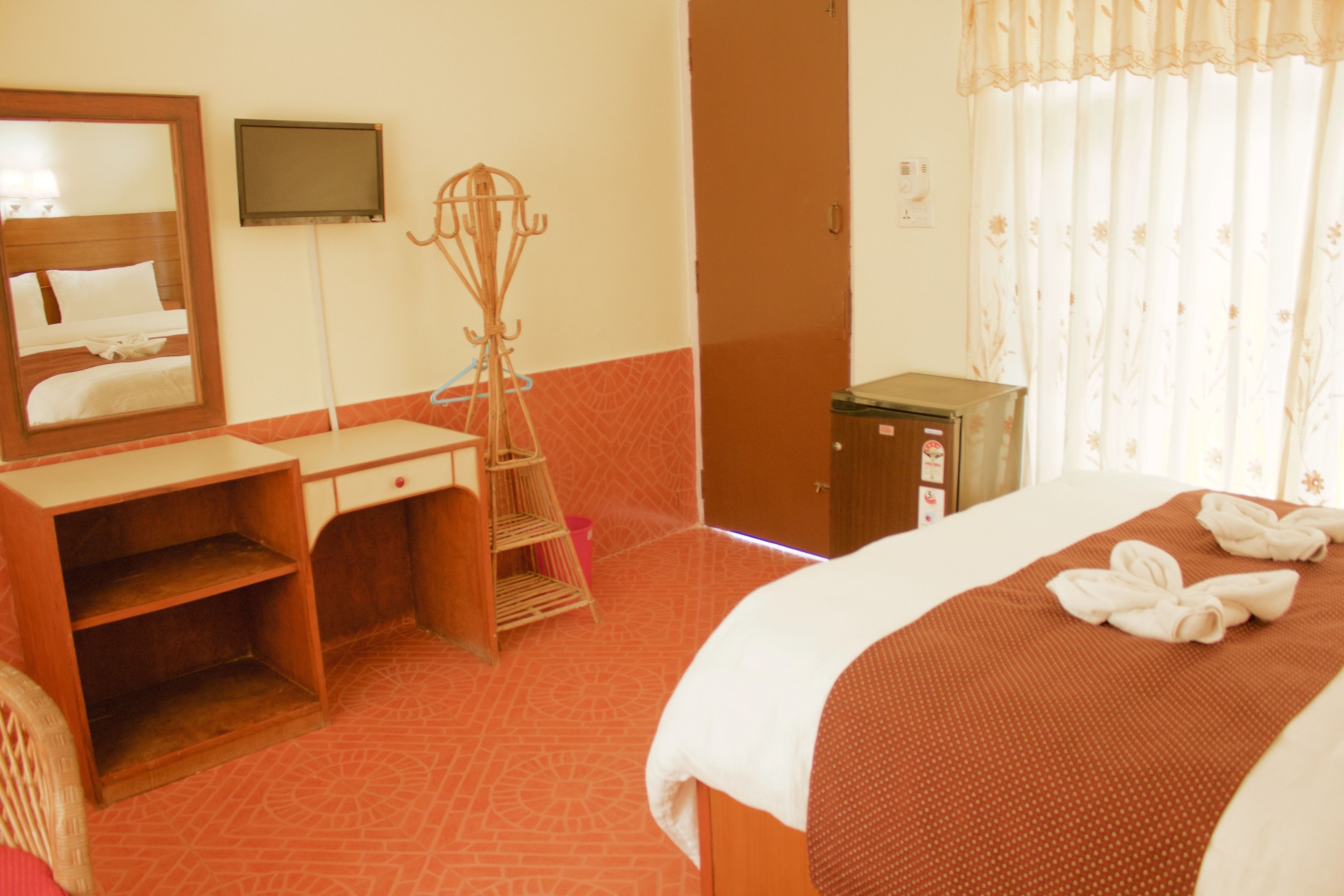 Une chambre d’hôtel comprenant un lit, un bureau en bois, une chaise, une télévision et une armoire.