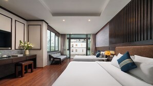 Une chambre d’hôtel avec un lit, un bureau, une chaise, un canapé et une grande fenêtre.