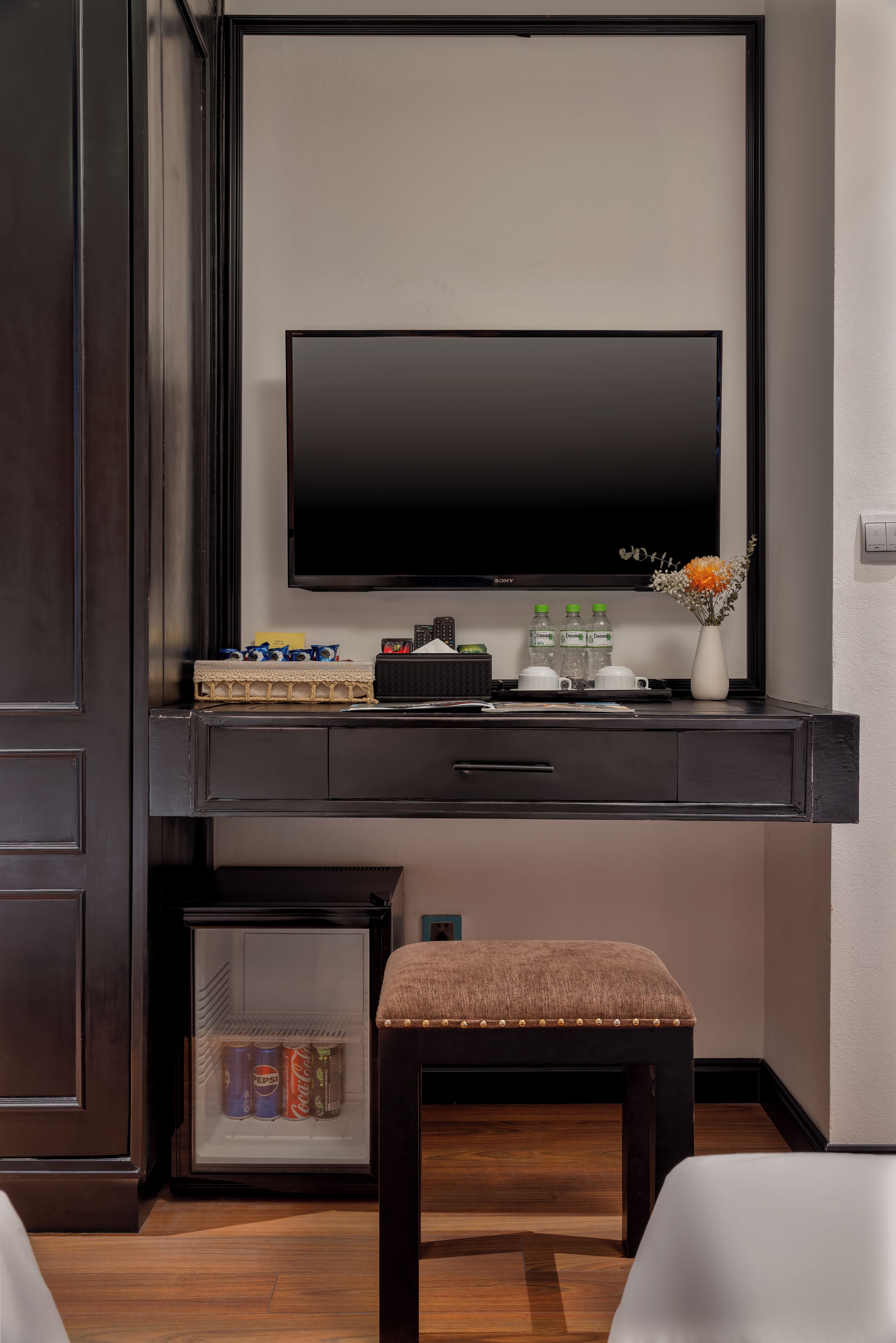 A modern room with a flat-screen TV, a small seating area, and a minibar.