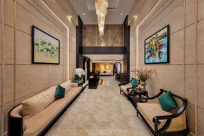 A hotel lobby with a marble floor, sofas, chairs, and artwork on the walls. - Ja Cosmo Premier Hotel (Hanoi)