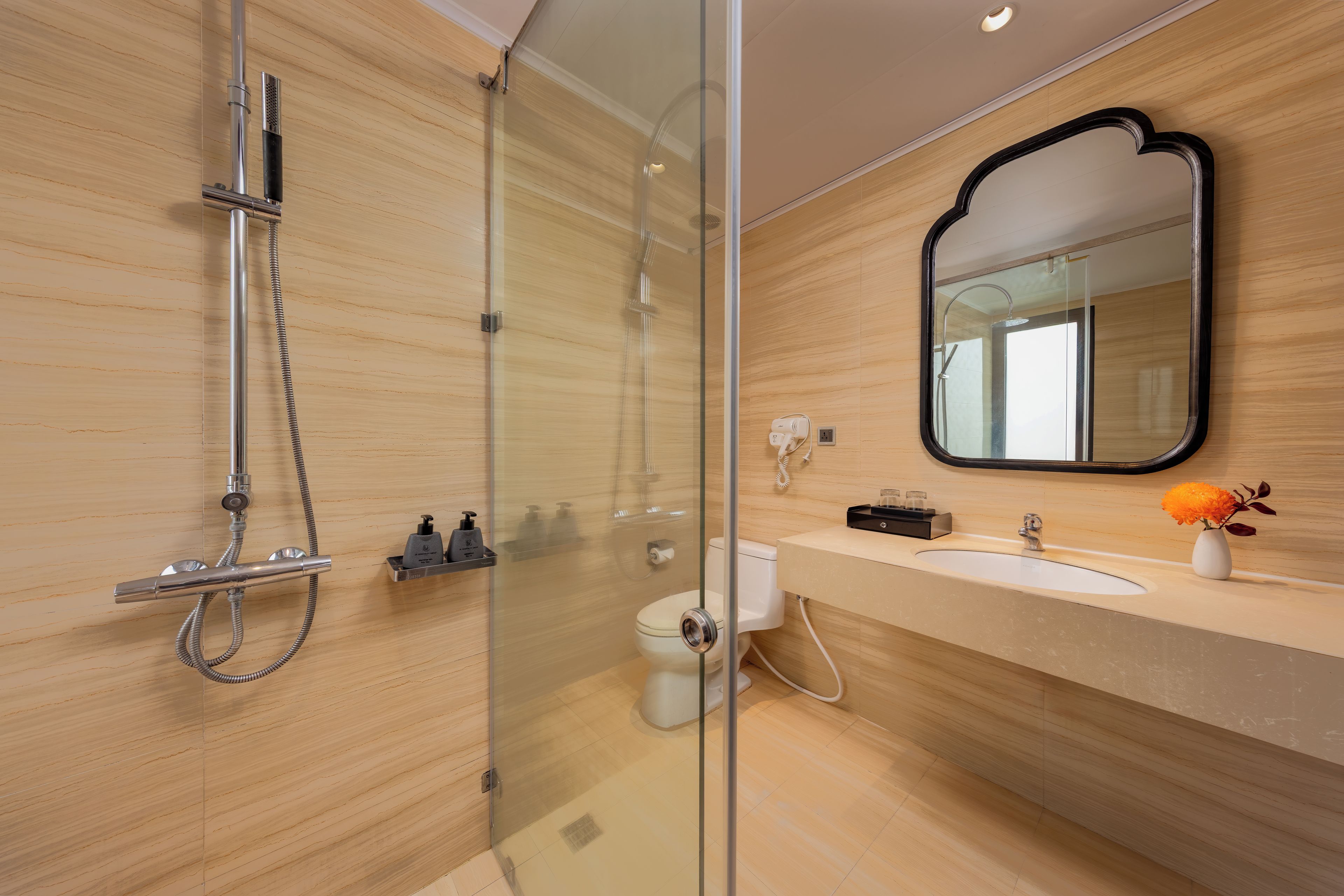 A modern bathroom with a glass-enclosed shower, a vanity with a sink, and a mirror.