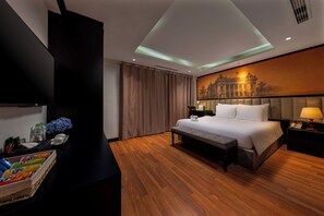 A hotel room with a bed, bedside table, lamp, and a wall-mounted TV.