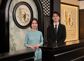 A reception desk with a logo and the text 'Premier Hotel Art of Elegance' in the background.