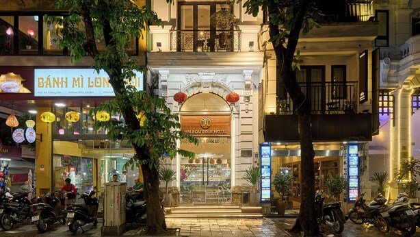 L’entrée d’un hôtel, avec une enseigne, un balcon et des motos garées.