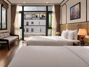 Una camera d'albergo con un letto grande, un divano, un comodino con una lampada e vista su un edificio.