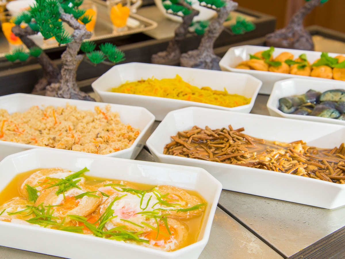 Variedad de platos en recipientes rectangulares blancos, incluyendo mariscos y fideos, dispuestos sobre una mesa.