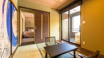 Um quarto japonês tradicional com tatames, uma mesa baixa e uma porta deslizante que dá para um quarto.