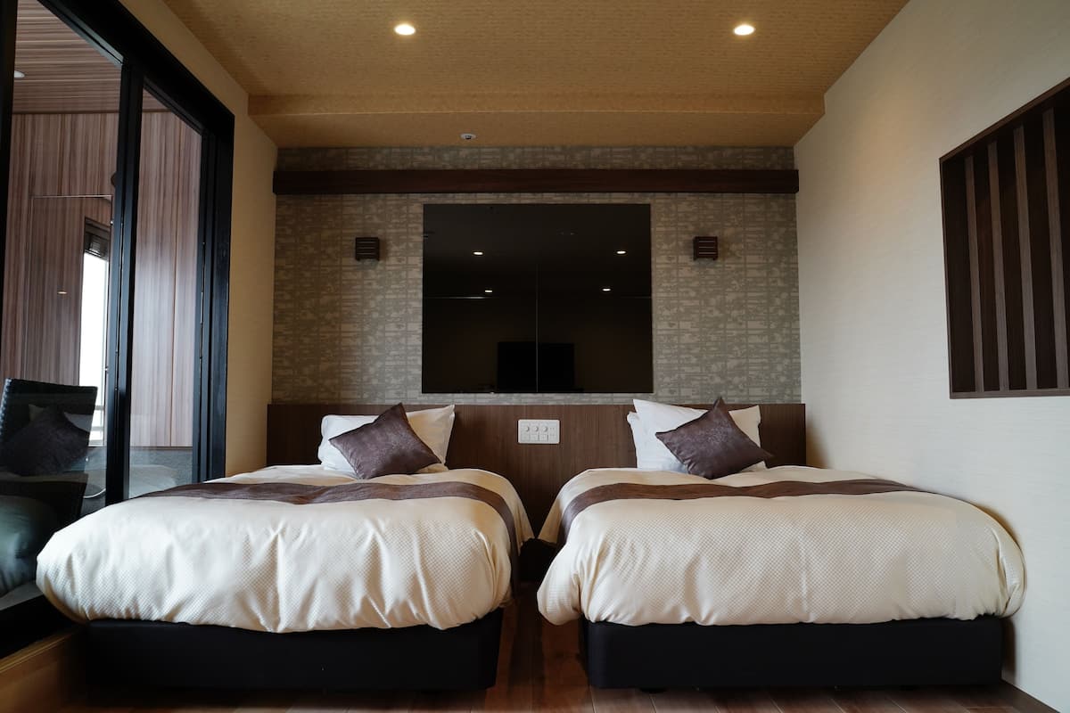 A hotel room with two beds, a large mirror, and a view of the outdoors.