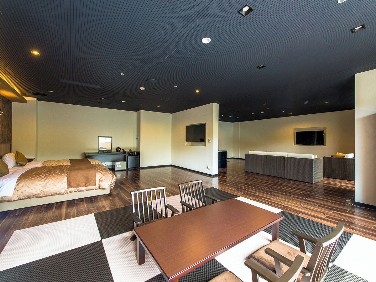 Une chambre d’hôtel moderne dotée d’un grand lit, d’une table à manger et d’un coin cuisine.