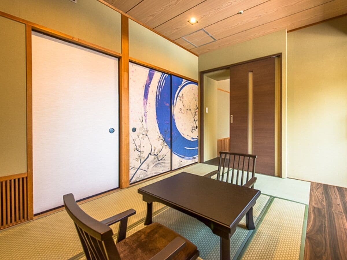 Una habitación japonesa tradicional con suelo de tatami, una mesita baja y puertas correderas shoji.