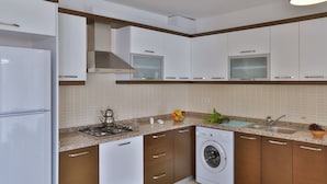 A modern kitchen with white cabinets, a built-in stove, a dishwasher, and a washing machine. - SC Apartments by Cinarlar (Kas)