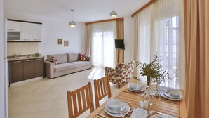 A modern living room with a dining area, a sofa, a TV, and a kitchen in the background. - SC Apartments by Cinarlar (Kas)