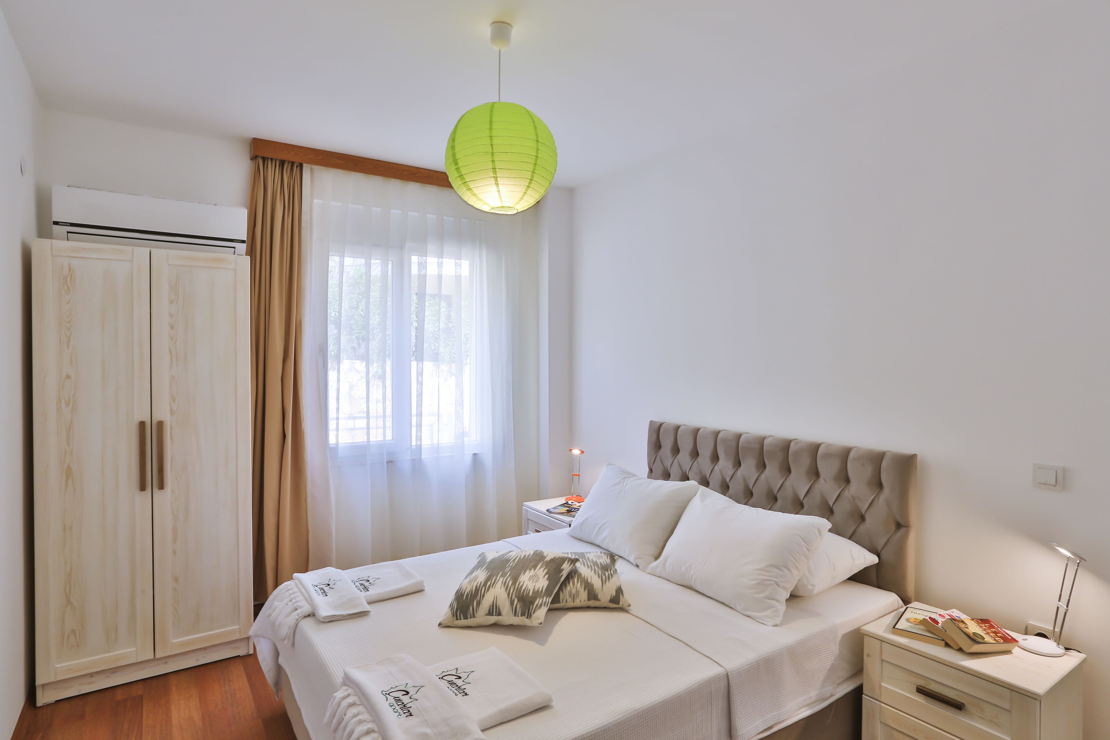 A bedroom with a bed, bedside tables, a wardrobe, and a window with curtains.