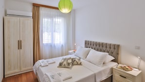 A bedroom with a bed, bedside tables, a wardrobe, and a window with curtains. - SC Apartments by Cinarlar (Kas)