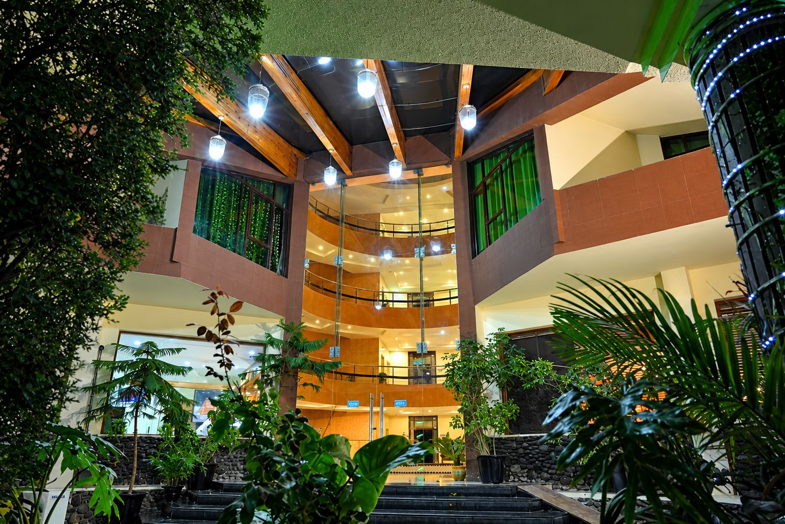 A multi-level atrium with a central staircase, surrounded by indoor plants and a modern architectural design.