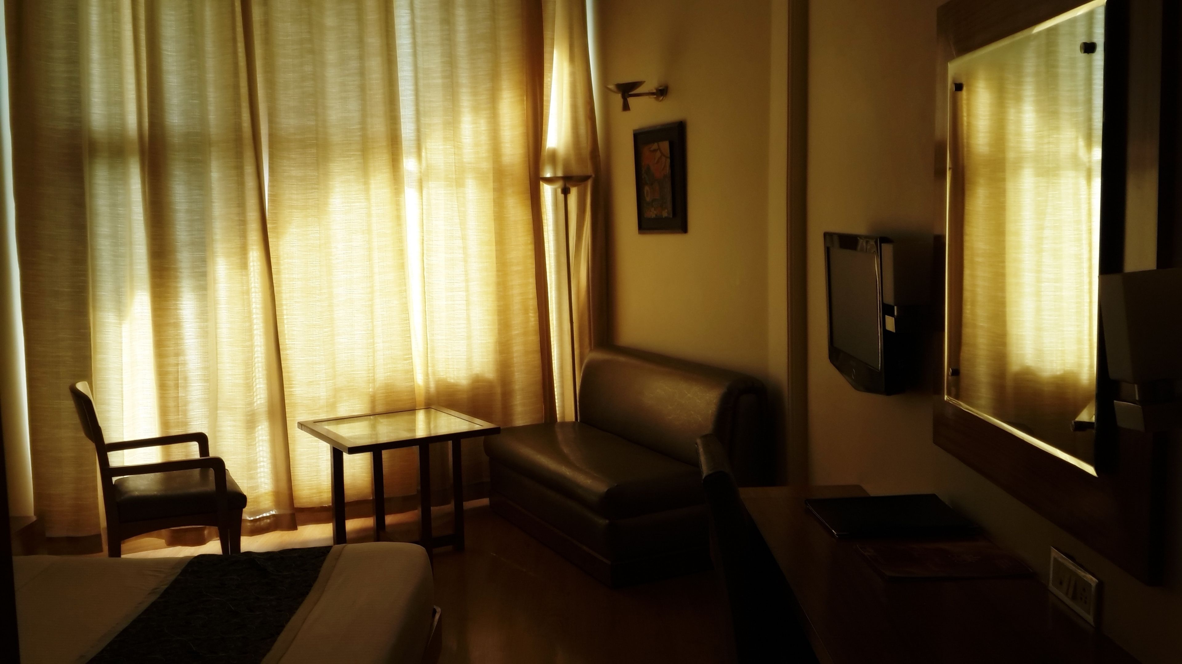 Una habitación de hotel con una cama, una mesita pequeña, un sofá y un televisor.