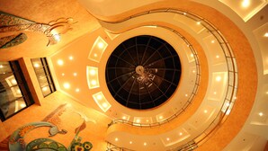 A multi-level atrium with a central circular skylight, multiple balconies, and a decorative ceiling. - Hotel Devi Grand (Reasi)