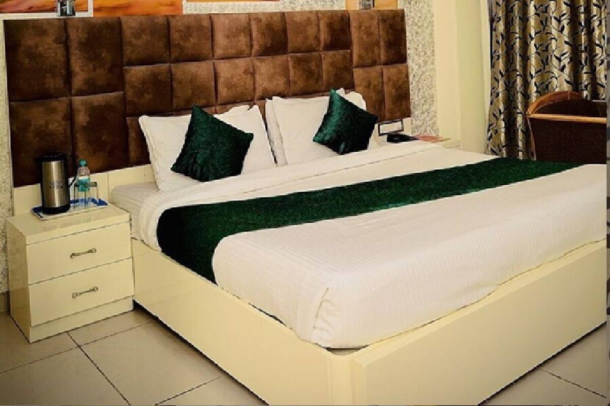 A neatly made bed with a brown headboard, white bedding, and green pillows.