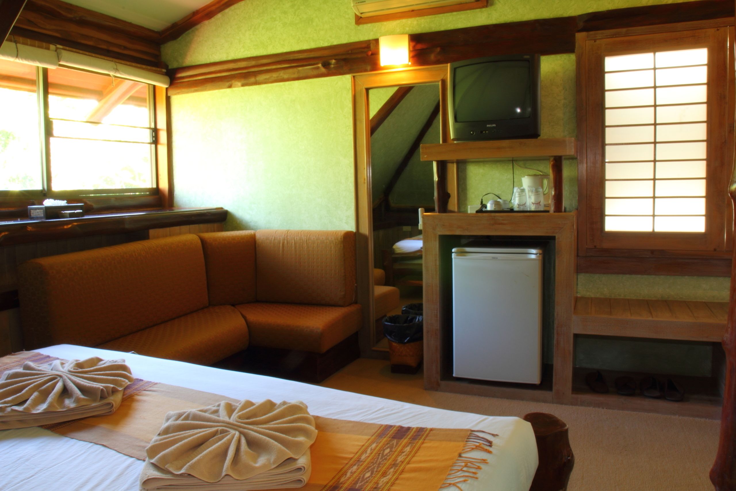 A cozy room with a bed, a sofa, a television, and a refrigerator.