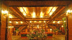 Un intérieur en bois agrémenté d’un arrangement floral central, de poutres en bois et d’un escalier.