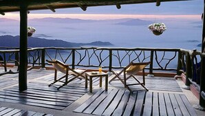 Une terrasse en bois avec deux chaises et une table, offrant une vue sur un paysage montagneux.