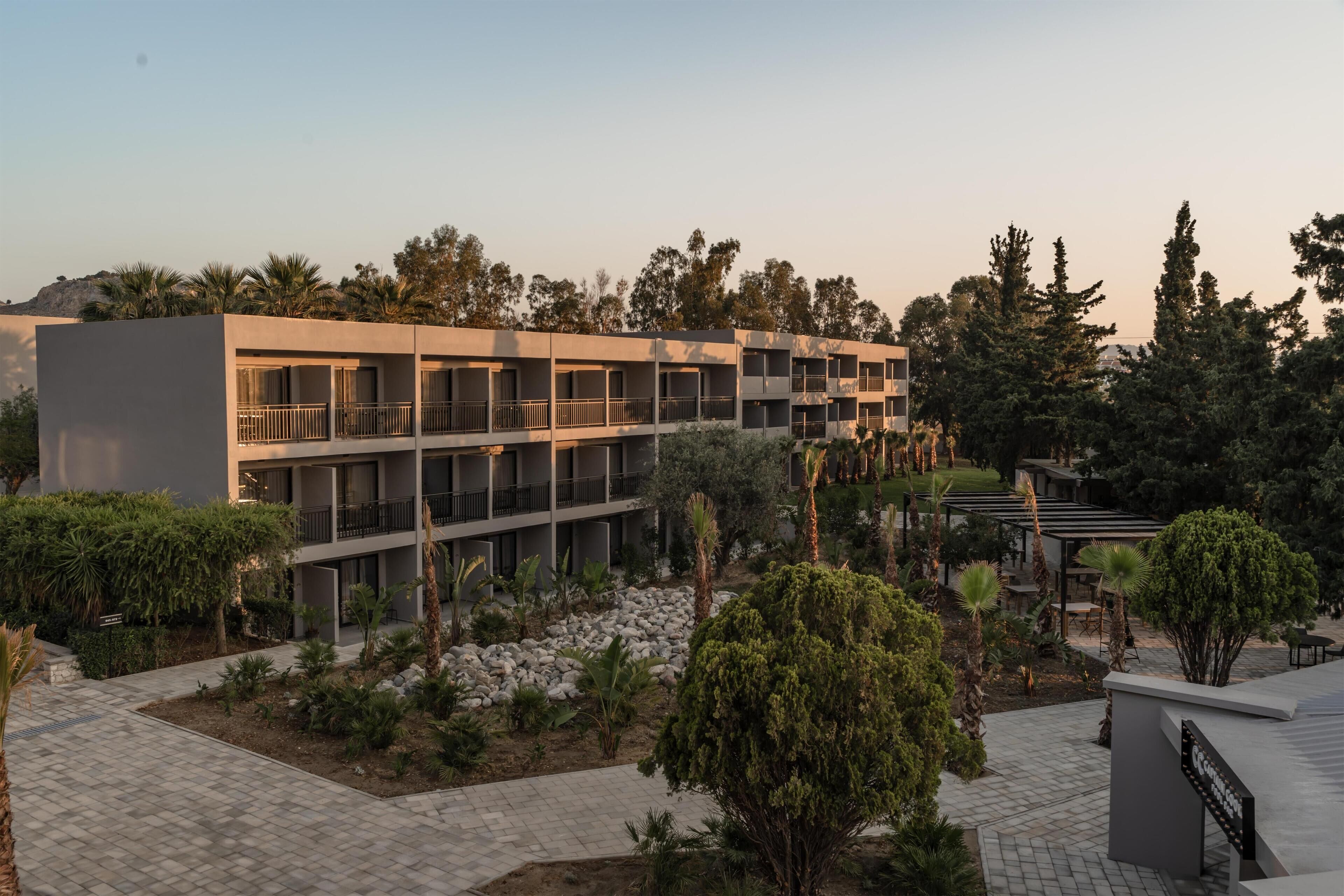 A modern hotel with multiple balconies, landscaped gardens, and a clear view of the surrounding area.
