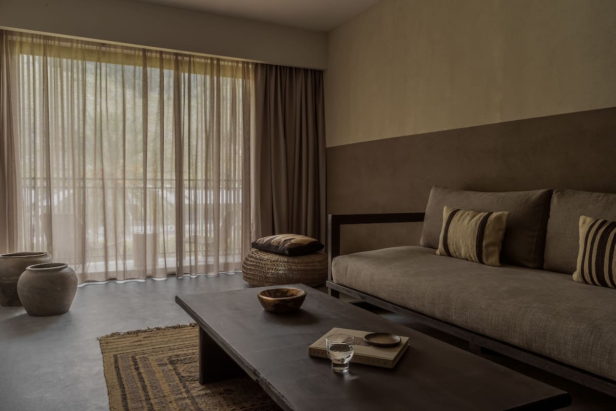 Una sala de estar moderna con un sofá, una mesa de centro y un ventanal con cortinas translúcidas.