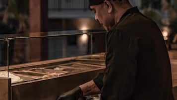Une personne travaille derrière un comptoir au design moderne, avec de grandes fenêtres et des luminaires suspendus.