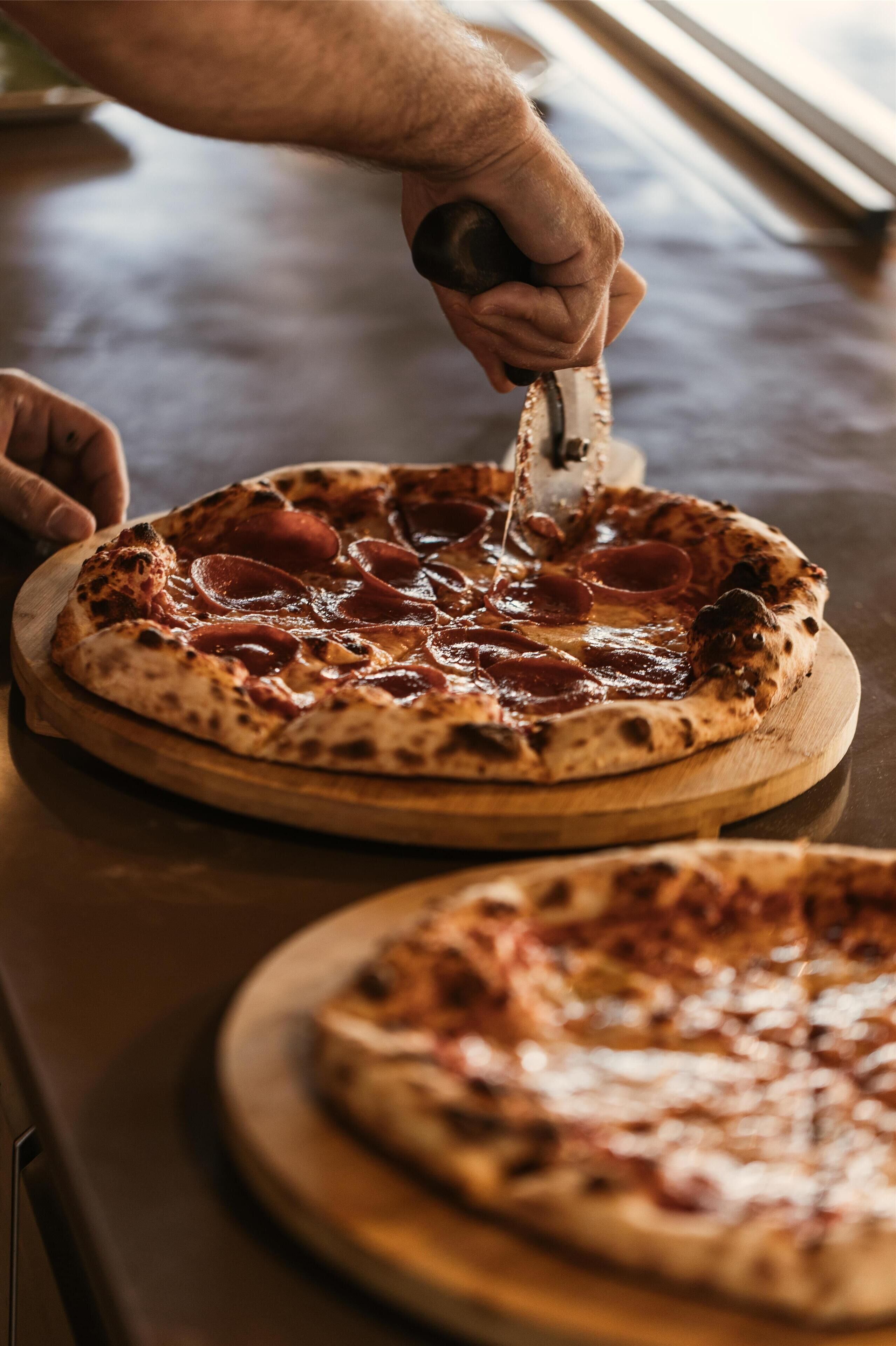 Pizza op een houten plank snijden.