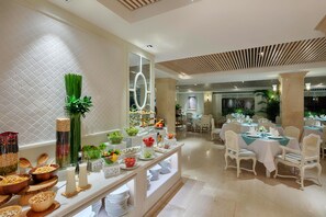 Un buffet proposant une variété de plats et un espace de restauration avec des chaises et des tables blanches.