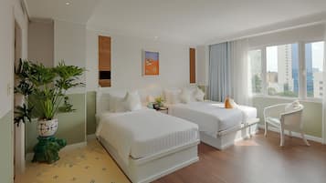 A hotel room with two beds, a potted plant, a chair, and a window with a city view.