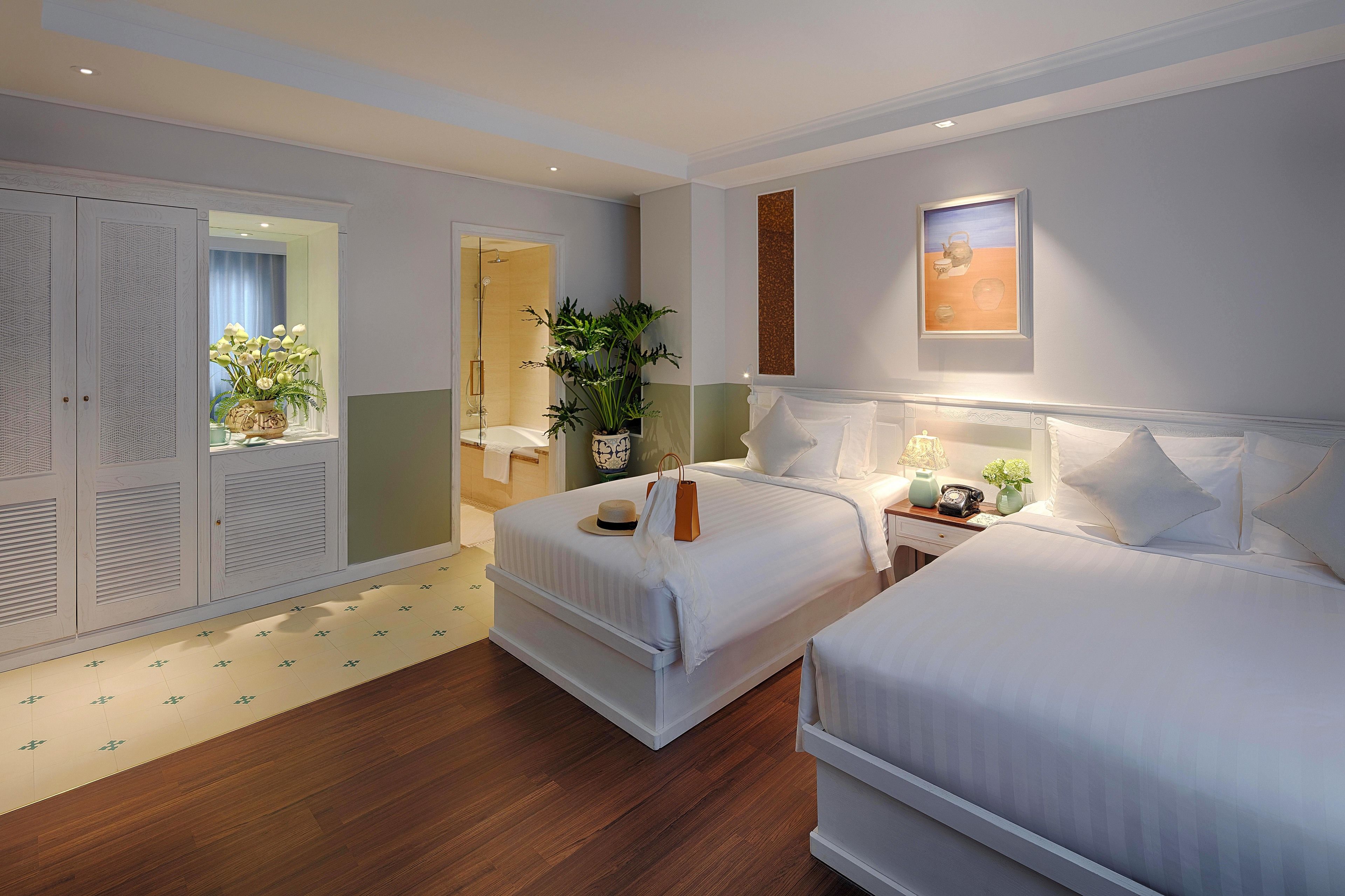 A hotel room with two beds, a bathroom, and a wardrobe.