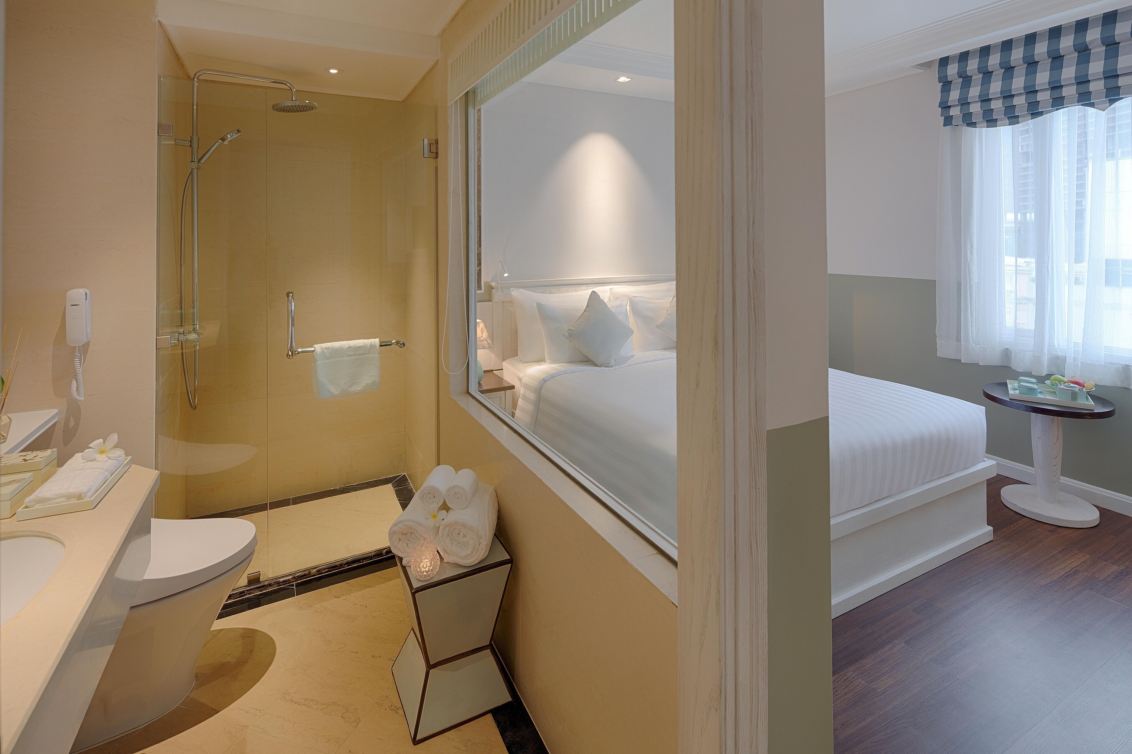 A hotel bathroom with a glass-enclosed shower, a toilet, and a sink.