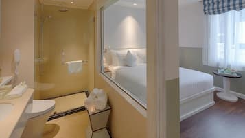 A hotel bathroom with a glass-enclosed shower, a toilet, and a sink.