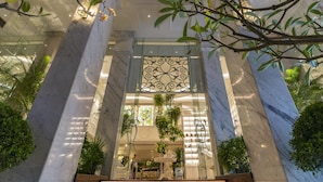 A lobby with marble columns, a glass partition with decorative metalwork, and indoor plants. - Au Lac Charner Hotel (Ho Chi Minh City)