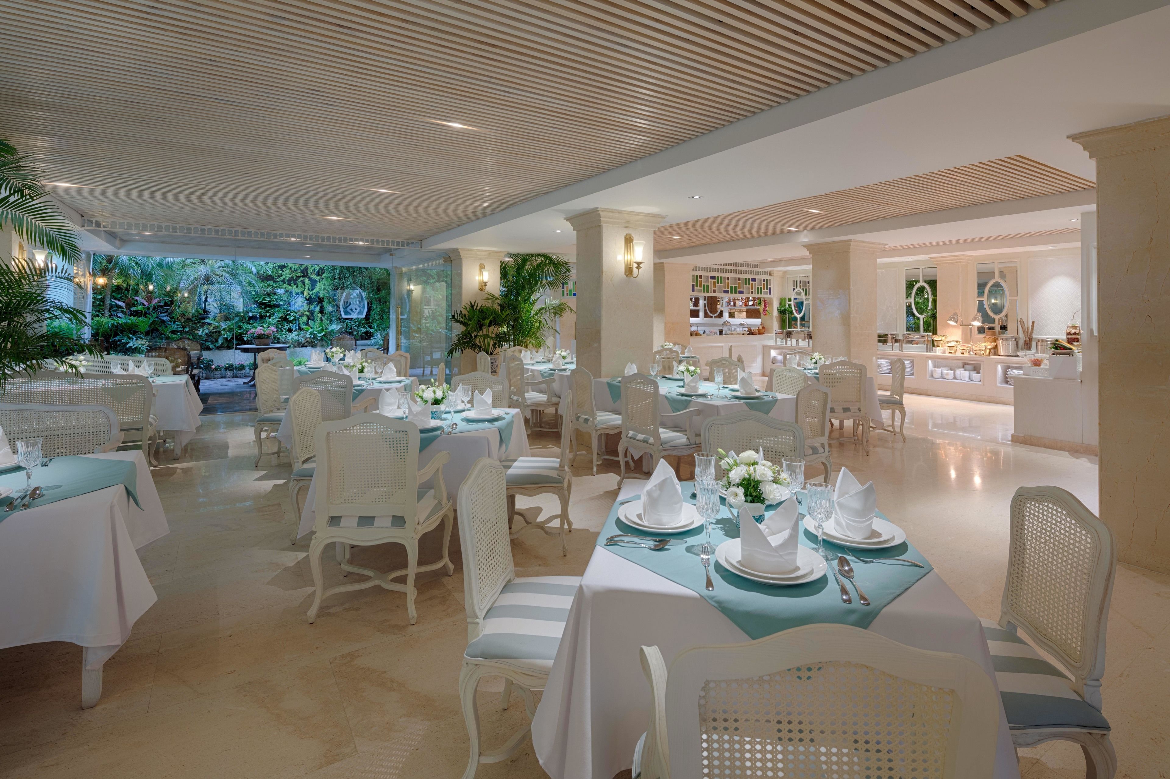 A spacious dining area with white furniture and tables set for a formal event.