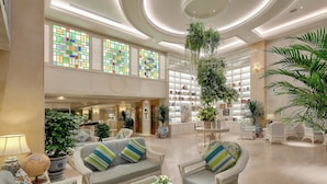 A spacious lobby with a high ceiling, large windows with colorful stained glass, and a variety of seating arrangements including sofas and chairs. - Au Lac Charner Hotel (Ho Chi Minh City)