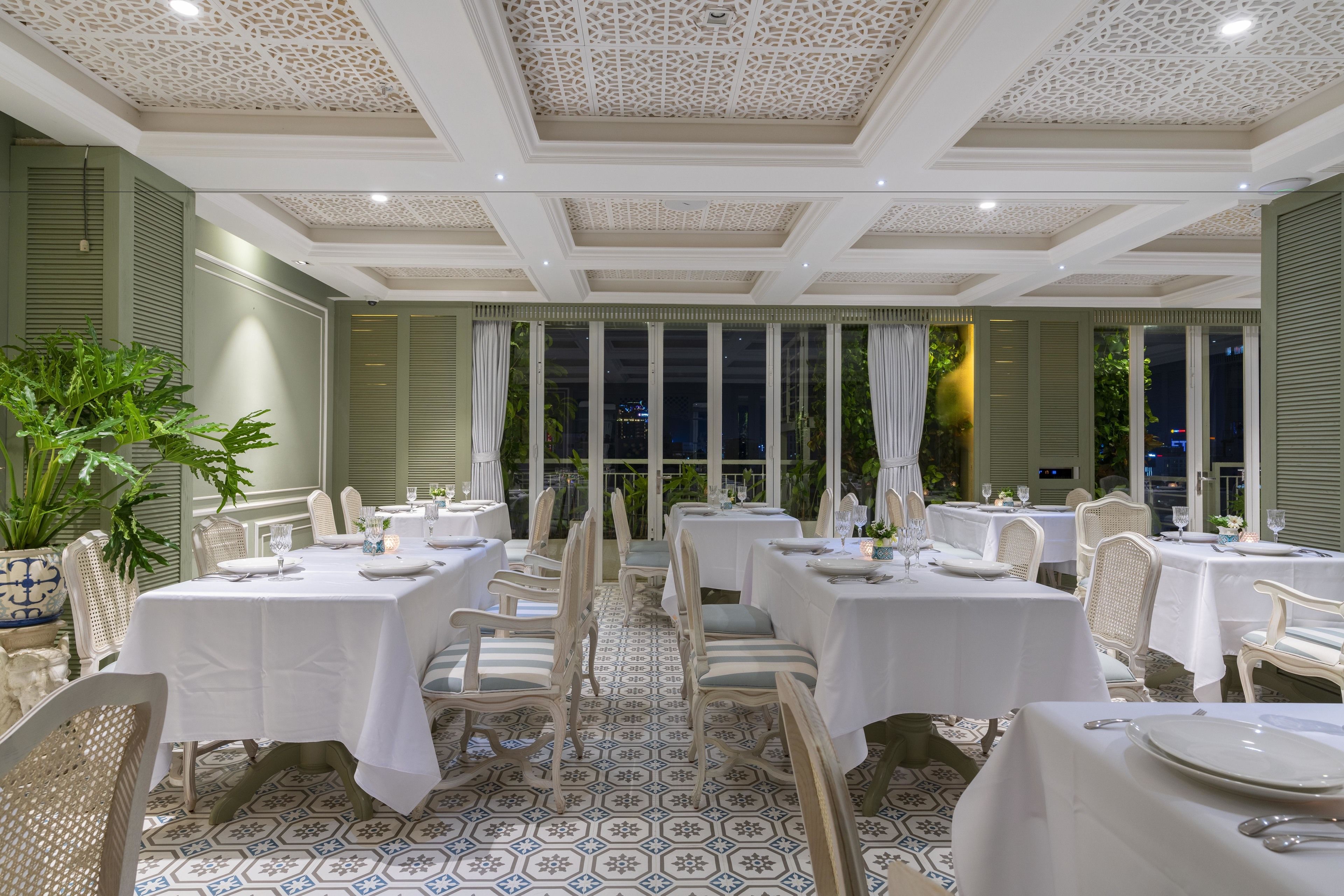 Comedor con mesas dispuestas para el servicio, destacando un piso con diseño y un techo de detalles intrincados.