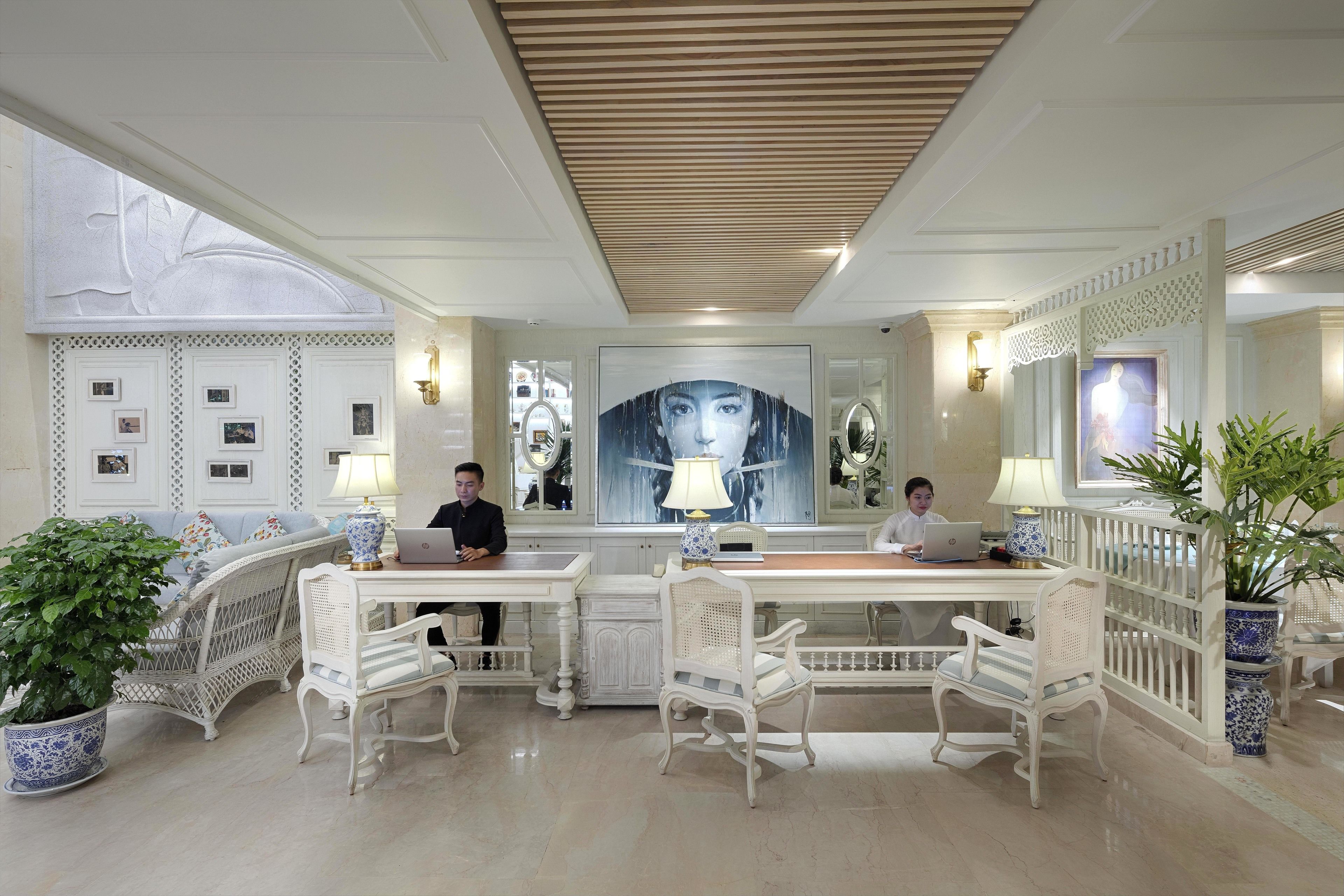 Une pièce spacieuse avec une table et des chaises au centre, un grand tableau au mur et une plante en pot.