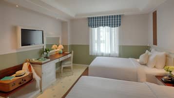 Une chambre d’hôtel avec deux lits, un bureau avec une chaise, une télévision et une fenêtre avec des rideaux.