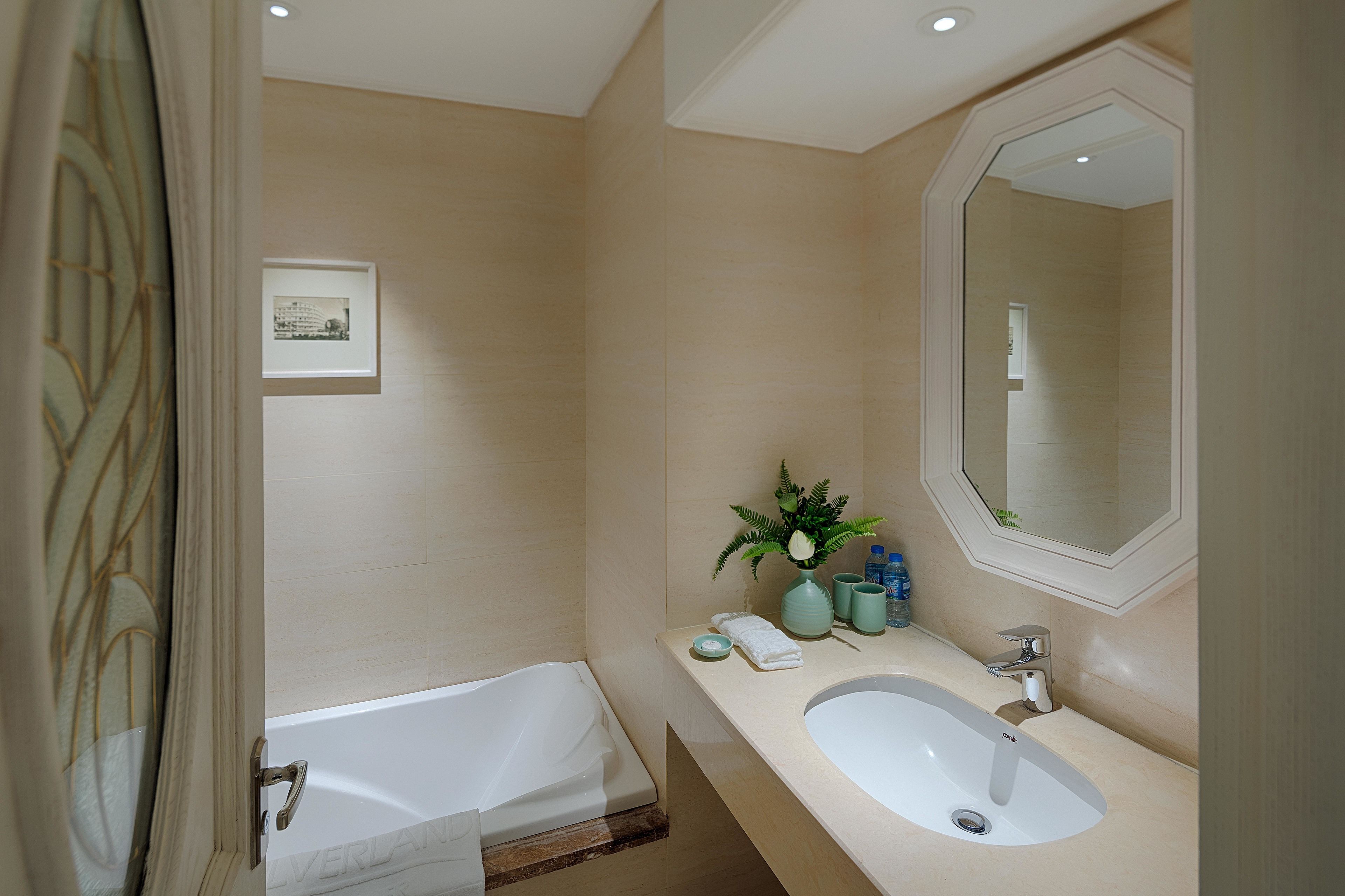 A bathroom with a bathtub, a sink, a mirror, and a framed picture on the wall.