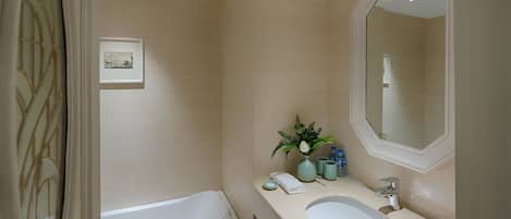 A bathroom with a bathtub, a sink, a mirror, and a framed picture on the wall.