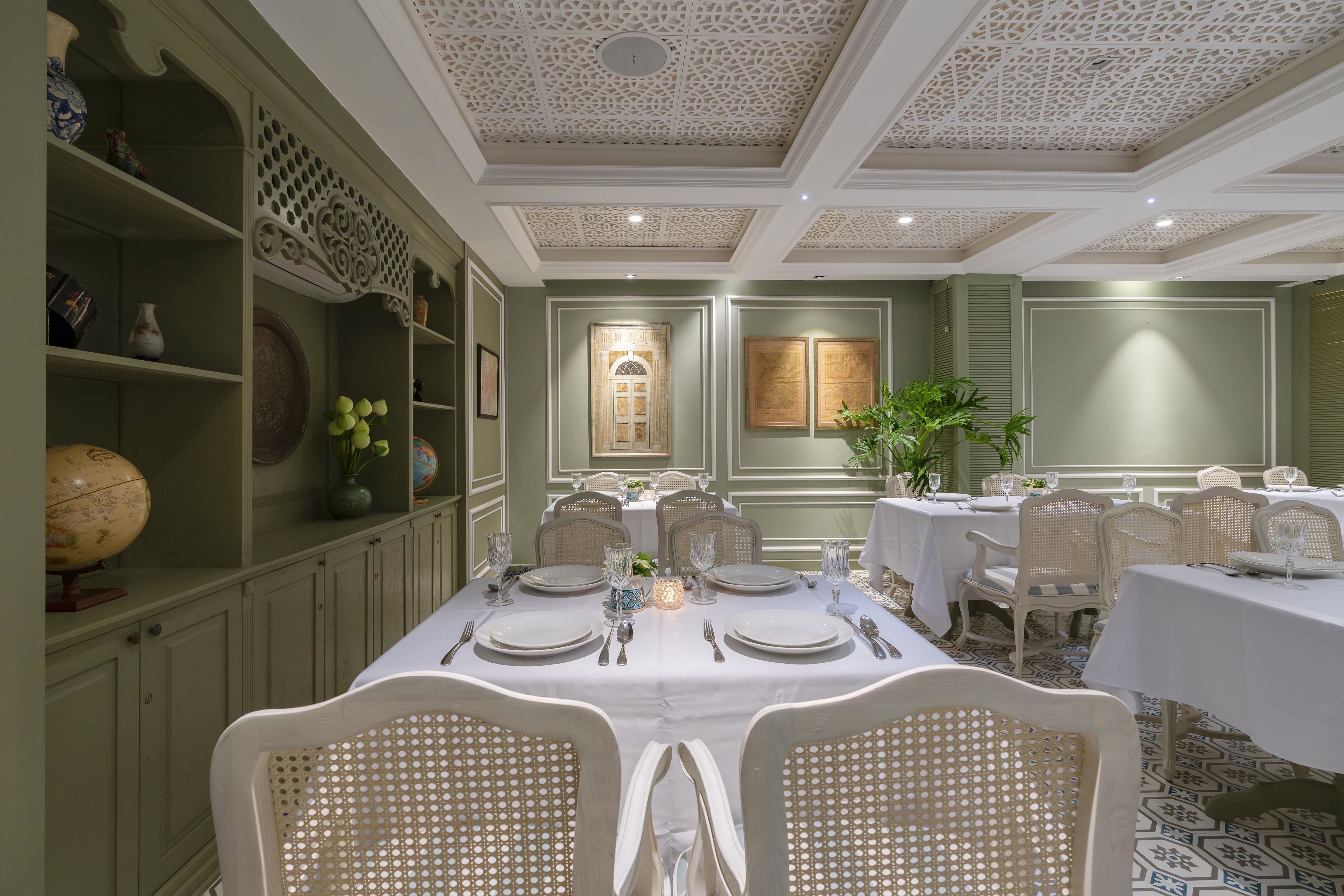 A dining area with a long table set for a meal, surrounded by white chairs with a perforated design.