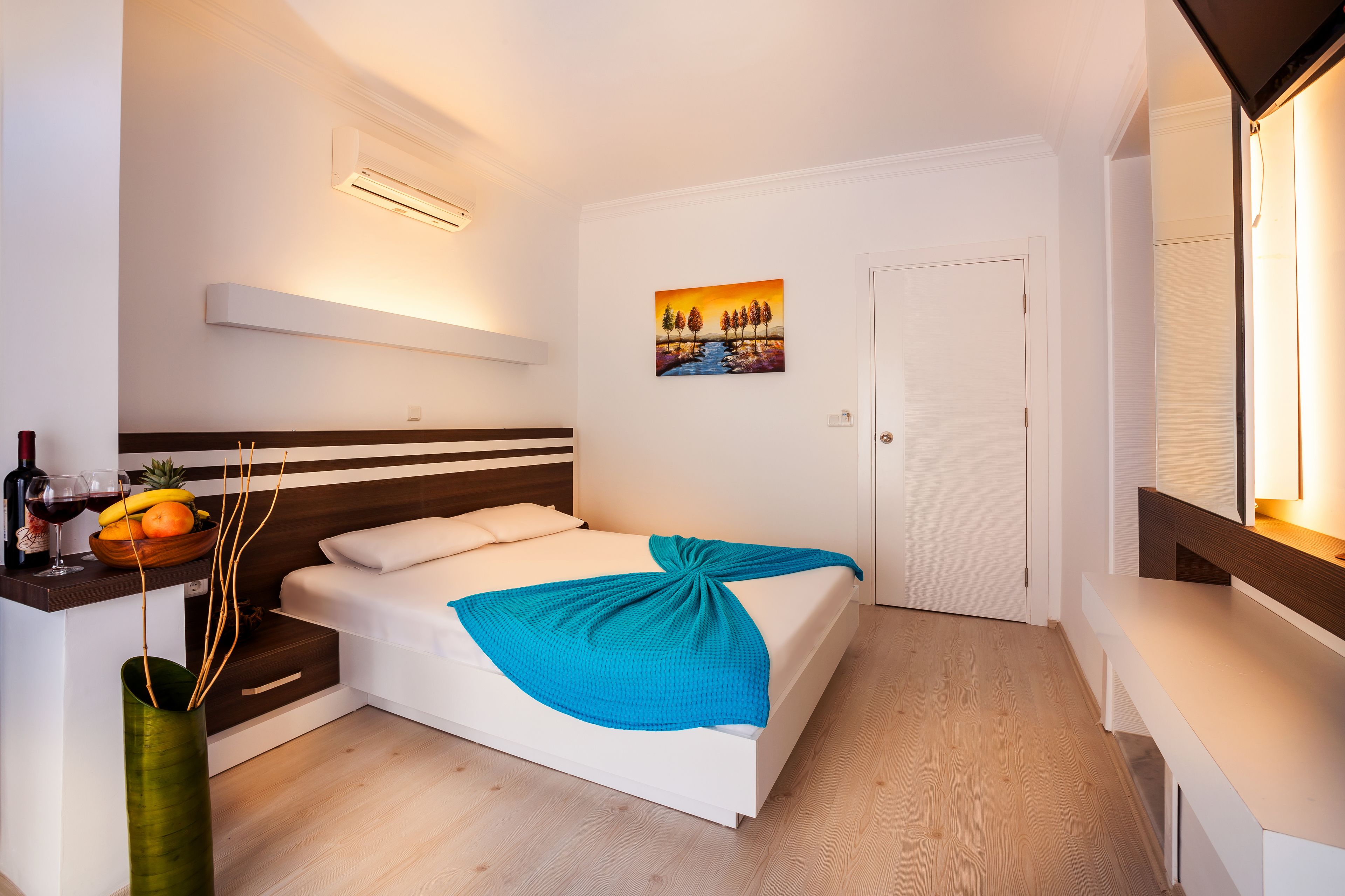 A modern bedroom with a bed, bedside table, and a painting on the wall.