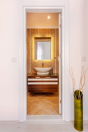 Un baño moderno con un espejo grande, un lavamanos blanco y un salpicadero de azulejos.