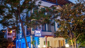Un hotel con un letrero que dice "HOTEL PUYA", diseño moderno en colores azul y blanco, una escalera que lleva a la entrada y plantas en macetas alrededor del área.